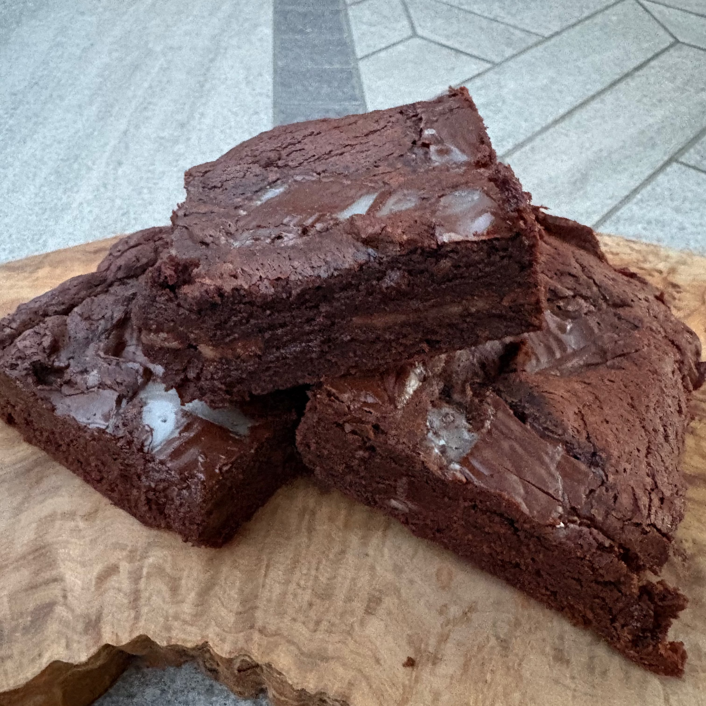 Three rich, dark After Eight chocolate brownies stacked on a rustic wooden board.