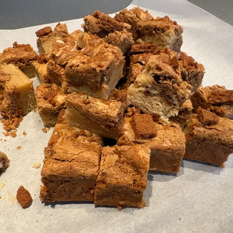 A pile of cut brownie bars with crumb topping, arranged on parchment paper.