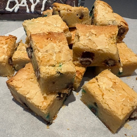 A pile of freshly baked chocolate chip cookie bars stacked on parchment paper.