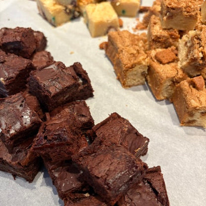 An assortment of cut brownies and chocolate-flecked squares arranged on white parchment paper.