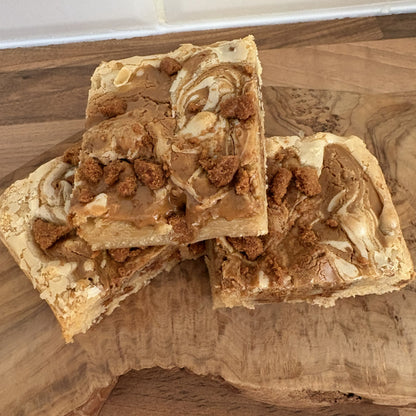 Three square pieces of biscoff blondie  on a wooden surface.